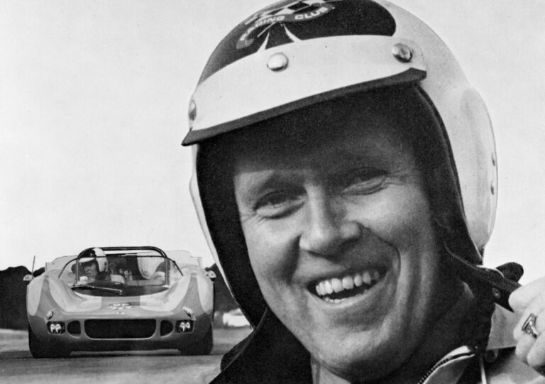 Svartvitt vykort från BP Racing Club med Sven-Olof ”ESSO” Gunnarsson iförd tävlingshjälm i förgrunden. I bakgrunden en McLaren.
